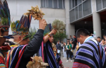 Indígenas con gorros hechos con plumas haciendo un ritual a un joven estudiante.