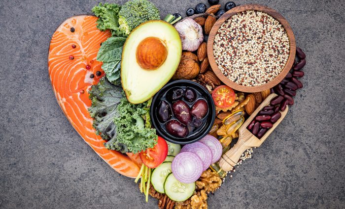 Heart shape of ketogenic low carbs diet concept. Ingredients for healthy foods selection on dark stone background. Balanced healthy ingredients of unsaturated fats for the heart and blood vessels.